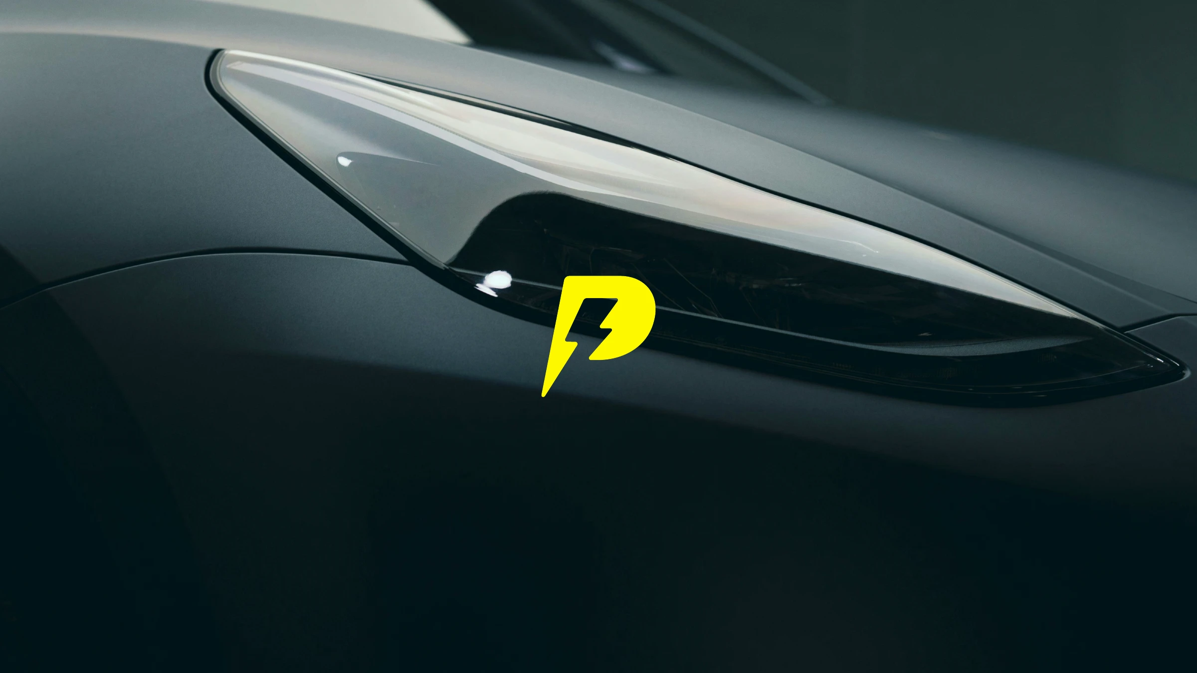 The yellow lightning 'P' mark set over the headlight of a dark sports car