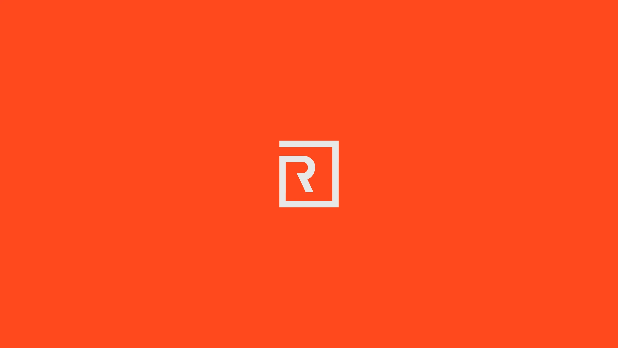 The monogram reversed in light grey on the orange-red brand background